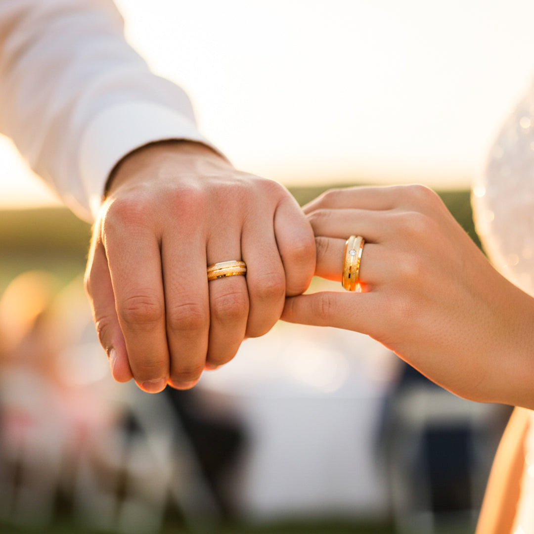 Manos de una pareja usando unas argollas de matrimonio facetadas en oro amarillo de 18 quilates con cristal de Joyería Caracas. 