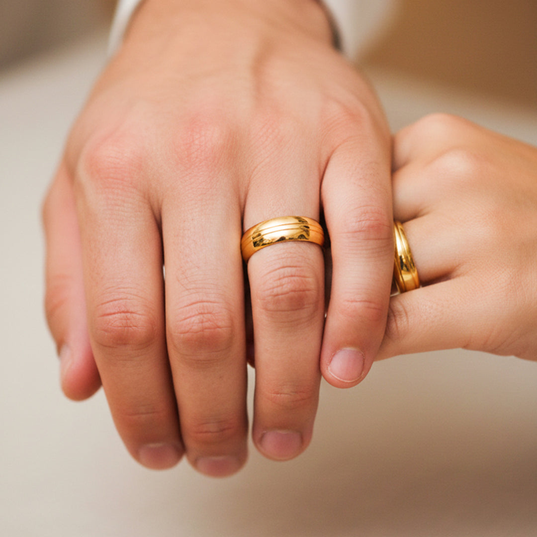 Manos de una pareja usando unas argollas en oro amarillo de 18 quilates de Joyería Caracas. 