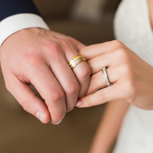 Manos de una pareja usando unas argollas de matrimonio en oro amarillo y blanco lisa, facetada y con cristales de Joyería Caracas. 