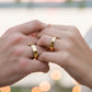Manos de una pareja usando unas argollas planas en oro amarillo de 18 quilates de Joyería Caracas.