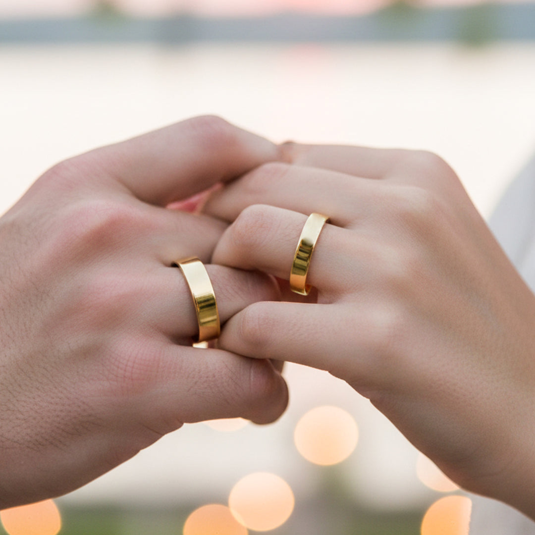 Manos de una pareja usando unas argollas planas en oro amarillo de 18 quilates de Joyería Caracas.