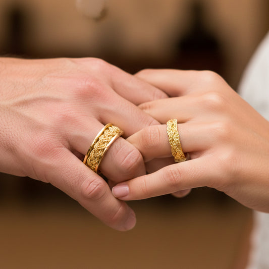 Manos de una pareja usando unas argollas en oro amarillo de 18 quilates trenzadas de Joyería Caracas.