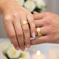 Manos de una pareja usando unas argollas de matrimonio en oro amarillo de 18 quilates de Joyería Caracas.