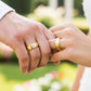 Manos de una pareja usando unas argollas de matrimonio en oro amarillo y blanco de 18 quilates de Joyería Caracas. 