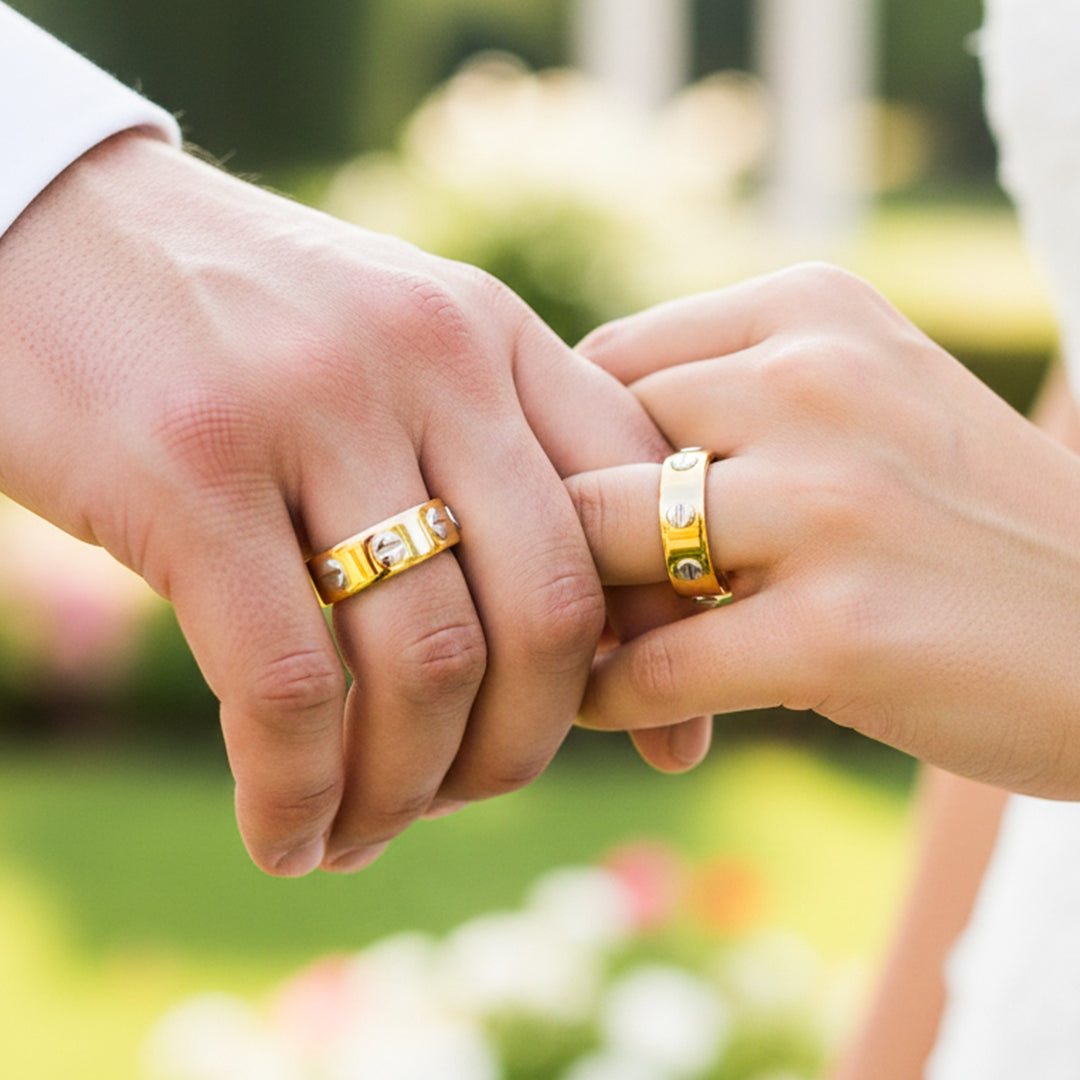 Manos de una pareja usando unas argollas de matrimonio en oro amarillo y blanco de 18 quilates de Joyería Caracas. 