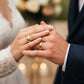 Manos de una pareja usando unas argollas de matrimonio en oro amarillo de 18 quilates con 3 cristales verdes de Joyería Caracas. 