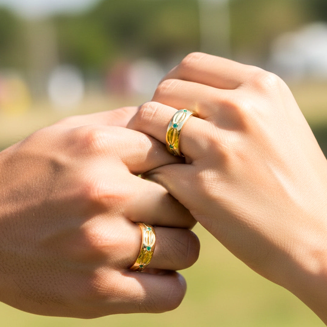 Mano de pareja usando unas argollas de matrimonio en oro amarillo de 18 quilates con cristales verdes de Joyería Caracas. 
