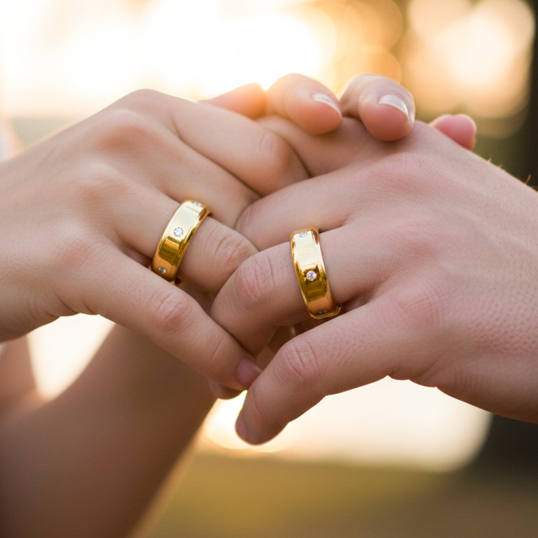 Manos de una pareja usando unas argollas en oro amarillo de 18 quilates de Joyería Caracas.