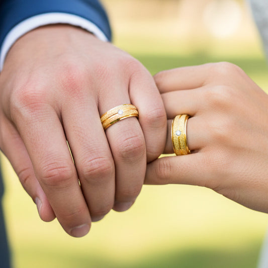 Manos de una pareja usando unas argollas de matrimonio facetadas en oro amarillo de 18 quilates con cristal de Joyería Caracas. 