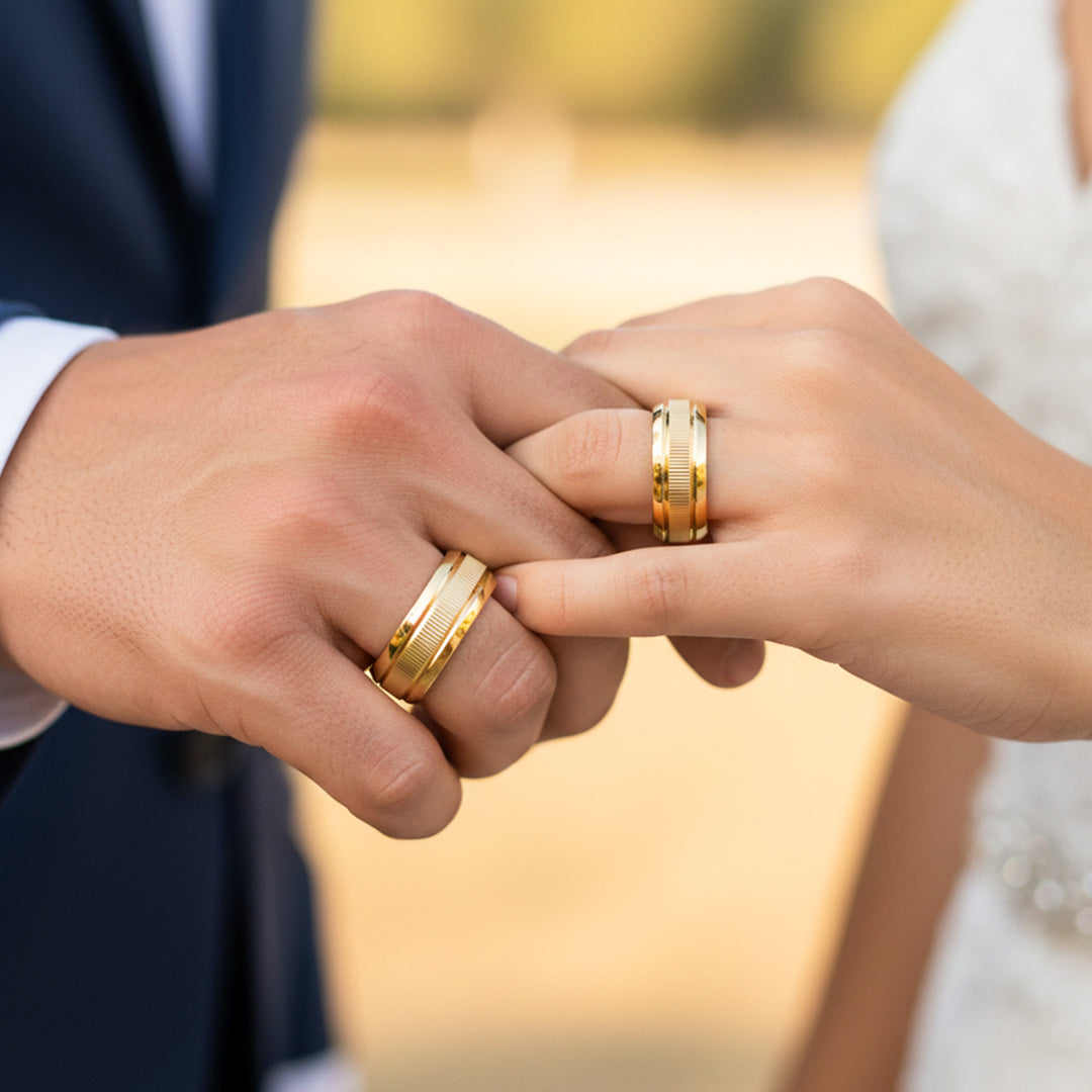 Manos de una pareja usando unas argollas de matrimonio en oro amarillo de 18 quilates de Joyería Caracas. 