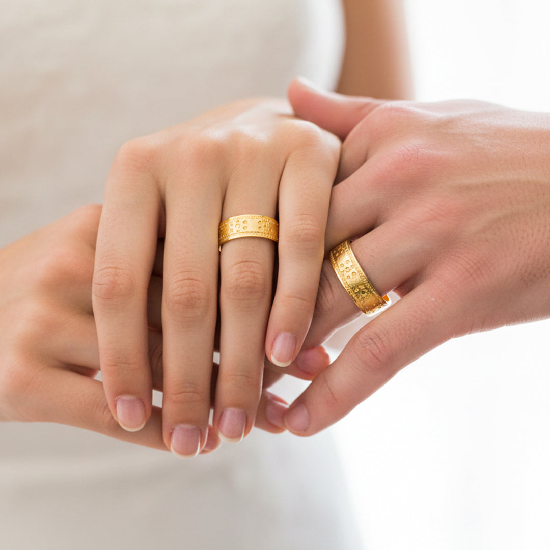 Manos de una pareja usando unas argollas en oro amarillo de 18 quilates de Joyería Caracas. 