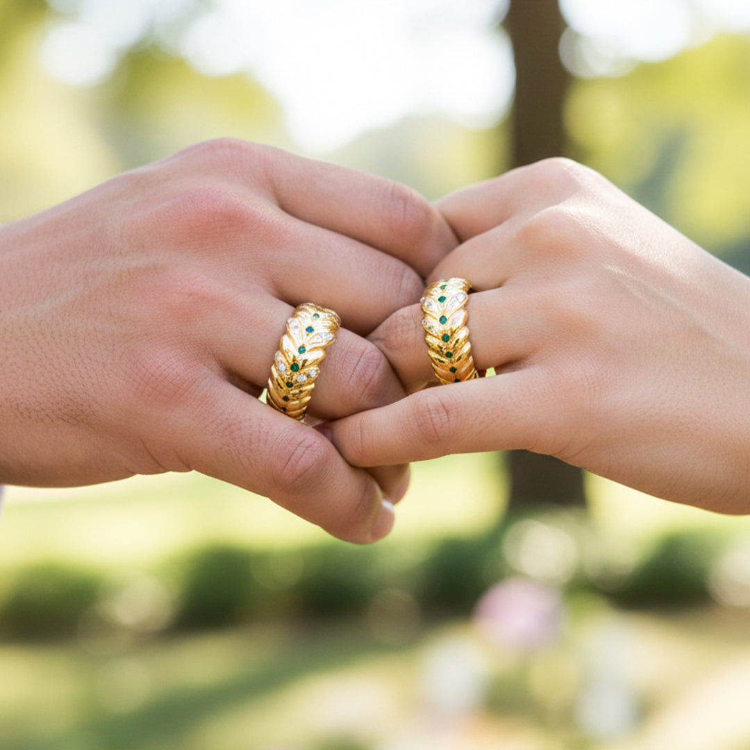 Manos de una pareja usando unas argollas de matrimonio en oro amarillo de 18 quilates con cristales verdes y blancos de Joyería Caracas. 
