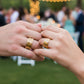 Manos de una pareja usando unas argollas de matrimonio con trenzado en oro amarillo, rosa y blanco de 18 quilates de Joyería Caracas. 
