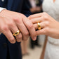 Manos de una pareja usando unas argollas en oro amarillo de 18 quilates de Joyería Caracas. 