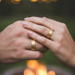 Manos de una pareja usando unas argollas en oro amarillo de 18 quilates de Joyería Caracas.