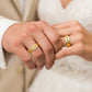 Manos de una pareja usando unas argollas en oro amarillo de 18 quilates con cristales verdes de Joyería Caracas. 
