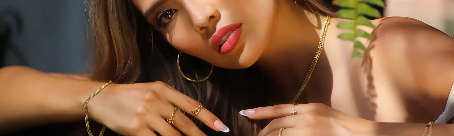 Plano cercano de una hermosa modelo con cadenas, aretes candongas y anillos, joyas en oro