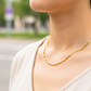 Cuello de modelo usando una cadena en tejido singapur en oro amarillo de 18 quilates de Joyería Caracas.