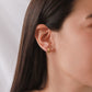 Oreja de mujer usando candongas con textura en líneas horizontales en oro amarillo de 18 quilates de Joyería Caracas.
