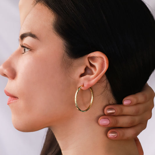 Oreja de mujer usando candongas square en forma de tubo con textura diamantada en oro amarillo de 18 quilates de Joyería Caracas.