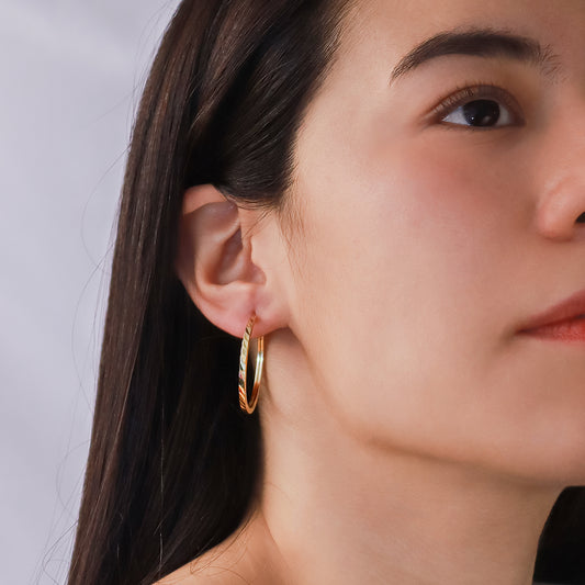 Oreja de mujer usando candongas square en forma de tubo con textura diamantada en oro amarillo de 18 quilates de Joyería Caracas.