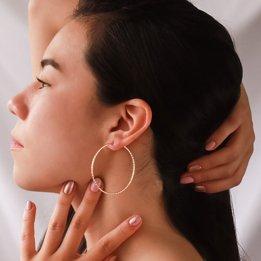 Oreja de mujer usando candongas square en forma de tubo con textura diamantada en oro amarillo de 18 quilates de Joyería Caracas.