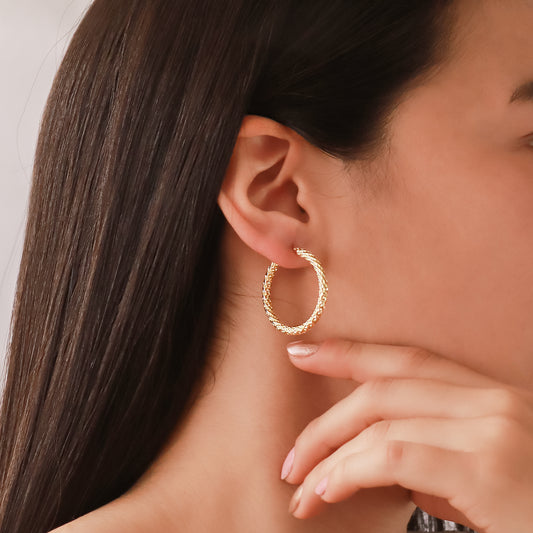 Oreja de mujer usando candonga con textura diamantada en oro amarillo de 18 quilates de Joyería Caracas.
