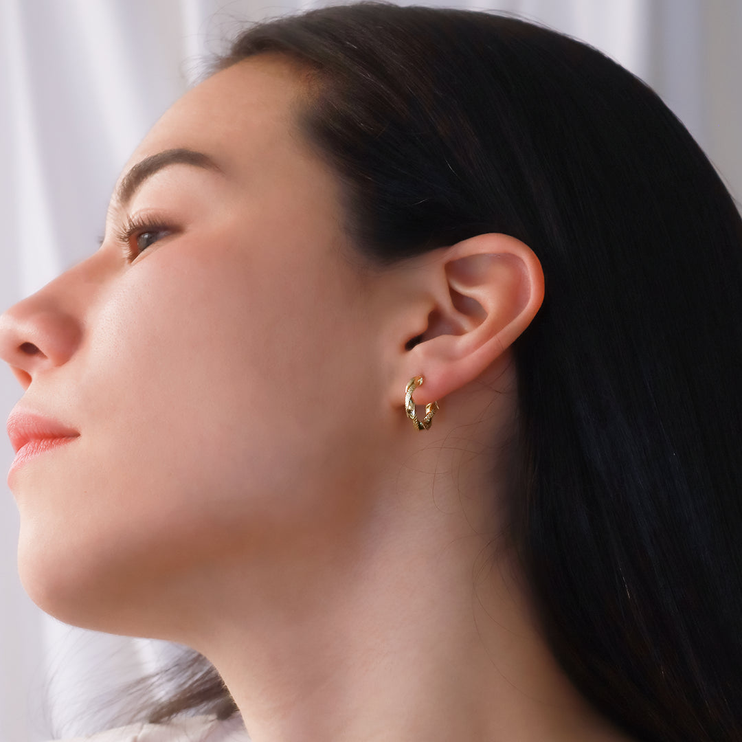 Oreja de mujer usando candongas en forma de melcocha en oro amarillo de 18 quilates de Joyería Caracas.