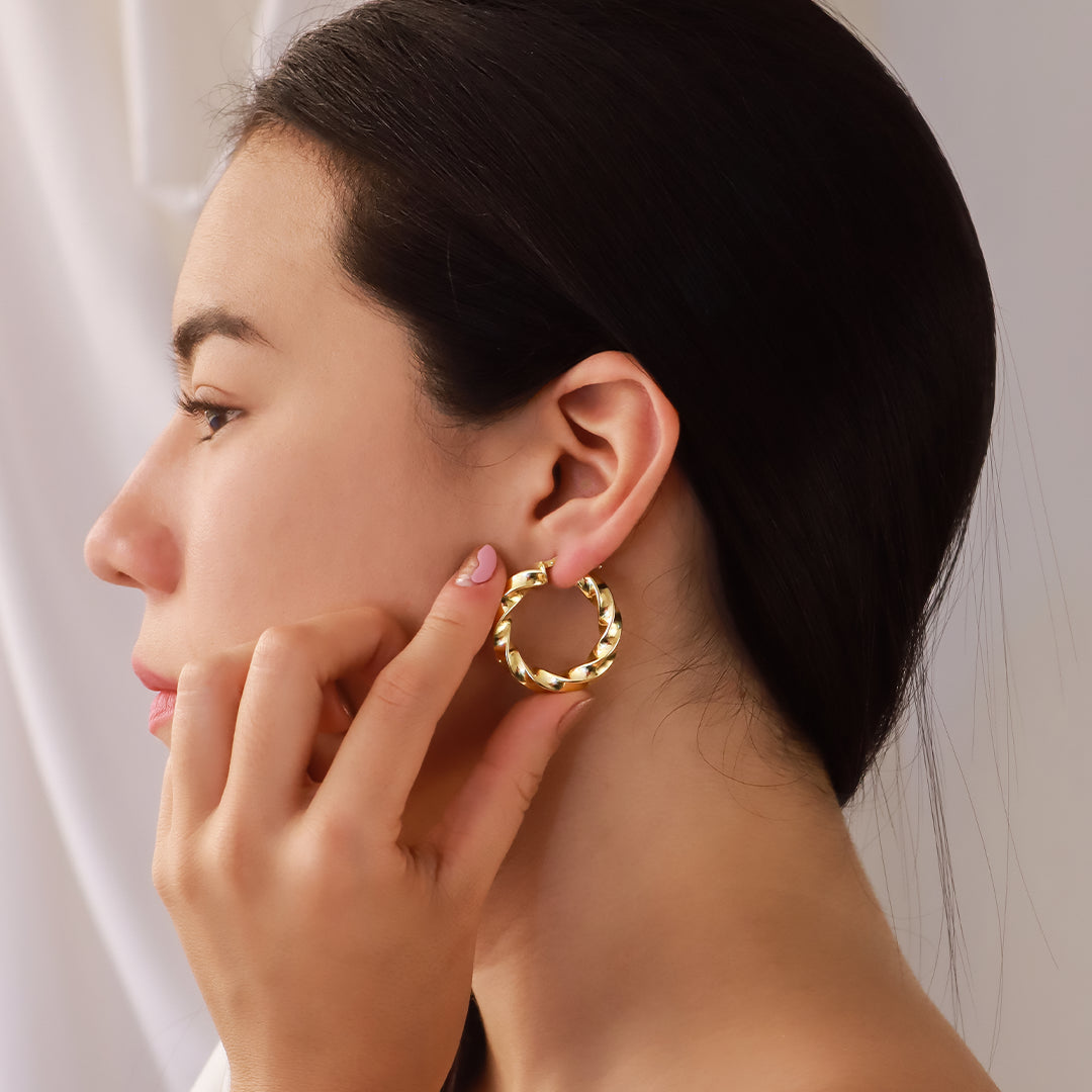 Oreja de mujer usando candongas en forma de melcocha en espiral en oro amarillo de 18 quilates de Joyería Caracas.