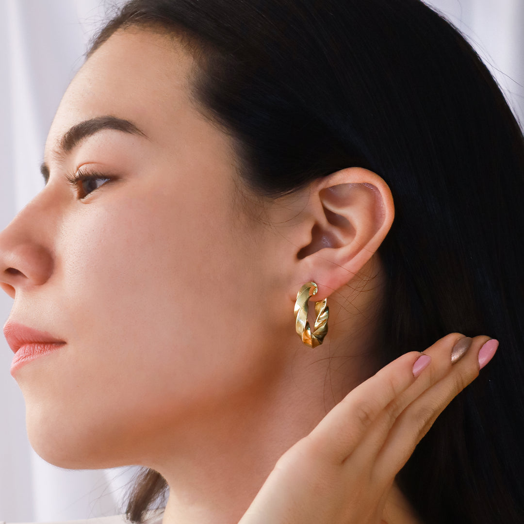 Oreja de mujer usando candonga en forma de melcocha con textura en apariencia de arena en oro amarillo de 18 quilates de Joyería Caracas.