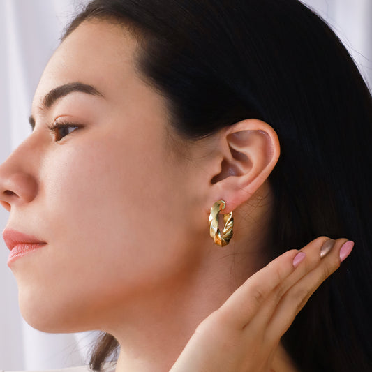 Oreja de mujer usando candonga en forma de melcocha con textura en apariencia de arena en oro amarillo de 18 quilates de Joyería Caracas.