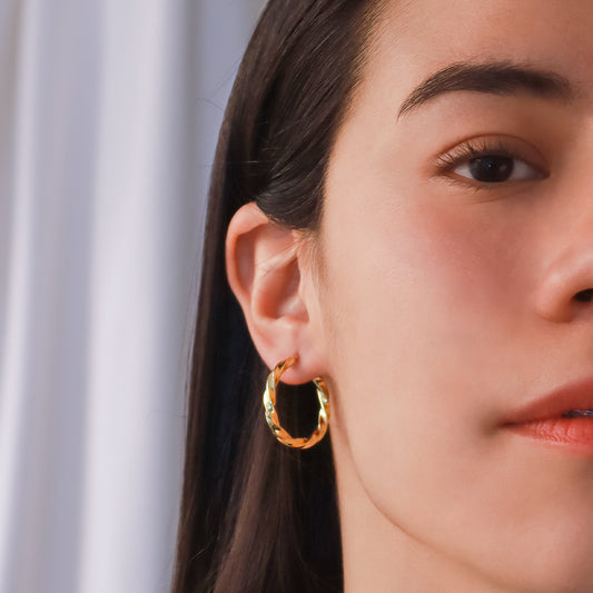 Oreja de mujer usando candongas en forma de melcocha en oro amarillo de 18 quilates de Joyería Caracas.