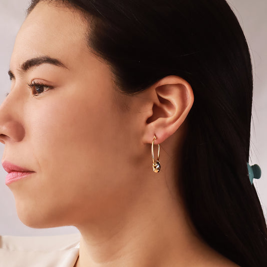 Oreja de mujer usando candonga con un nudo de 3 oros de 18 quilates de Joyería Caracas.