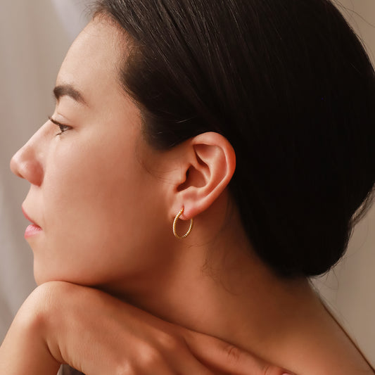 Oreja de mujer usando candongas en forma de tubo corrugadas en oro amarillo de 18 quilates de Joyería Caracas.