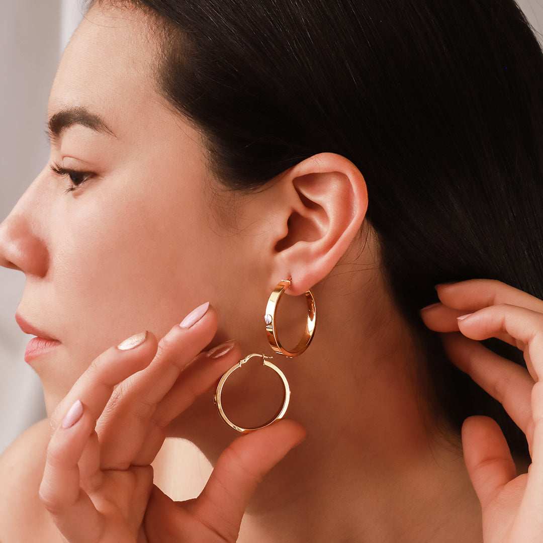 Oreja de mujer usando candongas en forma de tubo en oro amarillo con tornillos en oro blanco de 18 quilates de Joyería Caracas.