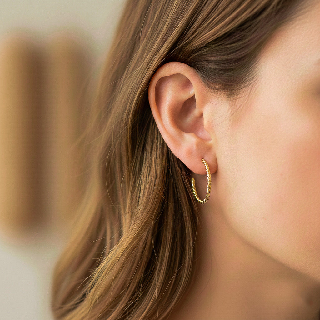 Oreja de modelo usando unas candongas entorchadas en oro amarillo de 18 quilates de Joyería Caracas. 