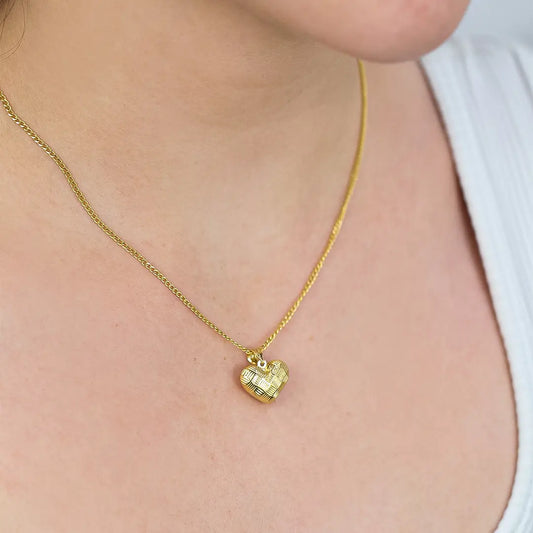 Cuello de mujer con cadena y dije con forma de corazón en oro amarillo de 18 quilates, hecho en Joyería Caracas. 
