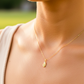 Cuello de modelo usando una cadena con un dije en forma de ala en oro amarillo de 18 quilates de Joyería Caracas.
