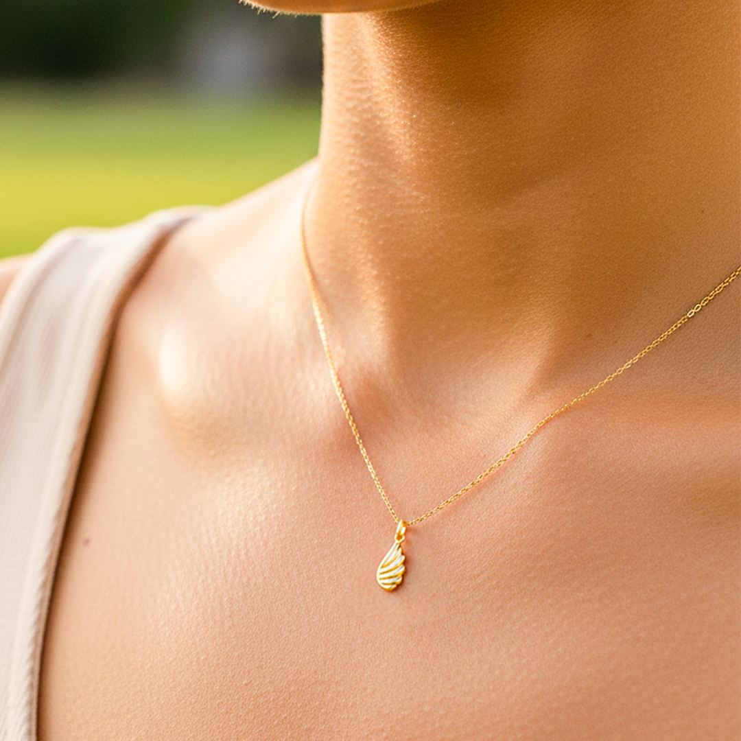 Cuello de modelo usando una cadena con un dije en forma de ala en oro amarillo de 18 quilates de Joyería Caracas.
