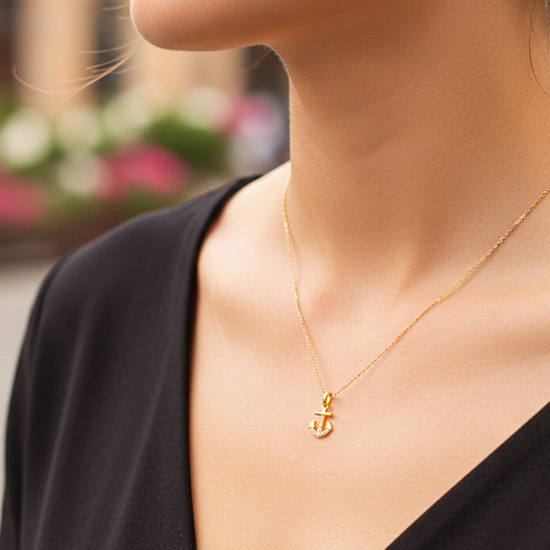 Cuello de modelo usando una cadena con un dije en forma de ancla en oro amarillo de 18 quilates con cristales de Joyería Caracas.