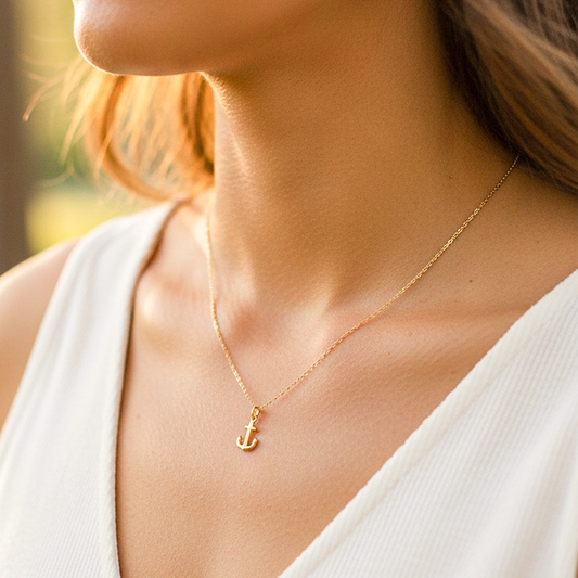 Cuello de modelo usando una cadena con un dije en forma de ancla en oro amarillo de 18 quilates de Joyería Caracas.