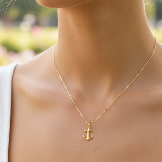 Cuello de modelo usando una cadena con un dije en forma de ancla en oro amarillo de 18 quilates de Joyería Caracas.