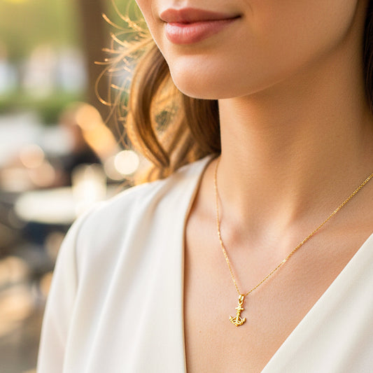Cuello de modelo usando una cadena con un dije en forma de ancla en oro amarillo de 18 quilates de Joyería Caracas.
