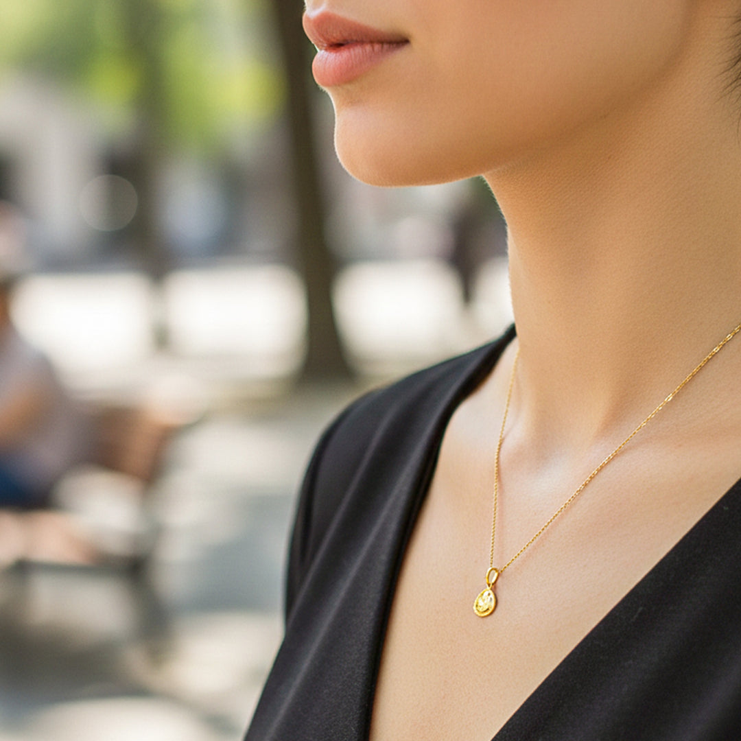 Cuello de modelo usando una cadena con un dije en forma de placa de angelito en oro amarillo de 18 quilates de Joyería Caracas.