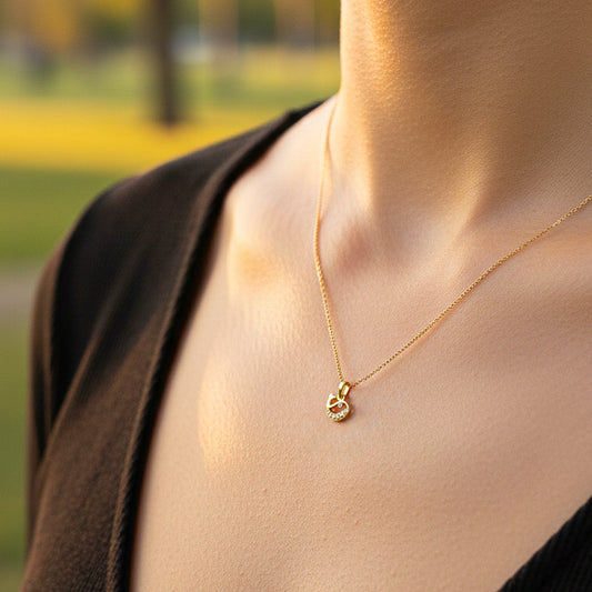 Cuello de modelo usando una cadena con un dije en forma ballena en oro amarillo de 18 quilates con cristal rosa de Joyería Caracas.