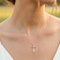 Cuello de modelo usando una cadena con un dije en forma de cruz abstracta en oro amarillo y blanco de 18 quilates de Joyería Caracas.