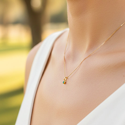 Cuello de modelo usando una cadena con un dije redondo en oro amarillo de 18 quilates con Esmeralda de Joyería Caracas.