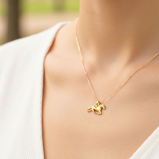 Cuello de modelo usando una cadena con un dije en forma de caballo en oro amarillo de 18 quilates de Joyería Caracas.