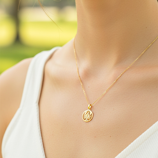 Cuello de modelo usando una cadena con un dije en forma del signo zodiacal de Cáncer en oro amarillo de 18 quilates de Joyería Caracas.