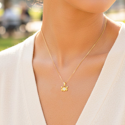 Cuello de modelo usando una cadena con un dije en forma de cangrejo en oro amarillo de 18 quilates con cristales de Joyería Caracas.